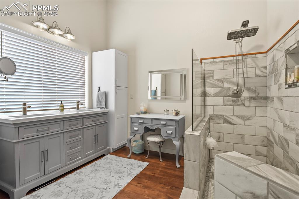 Image 19 of 41: Full bathroom with double vanity, a walk in Spa shower, and dark wood-type
