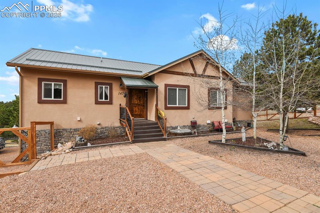 Image 2 of 41: View of front of home with stucco siding, a metal roof, and stone siding