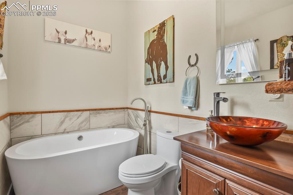 Image 6 of 41: Full bathroom with vanity, tile walls, a freestanding tub, and a wainscoted