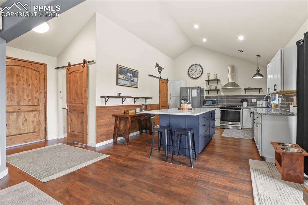 Image 7 of 41: Dual tone kitchen featuring a barn door, lofted ceiling, dual tone cabinetr