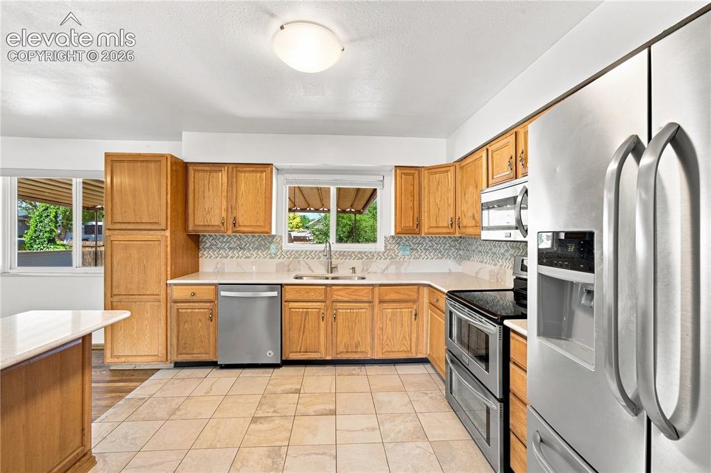 Image 12 of 39: Kitchen featuring light wood cabinetry, white countertops, tile flooring, s