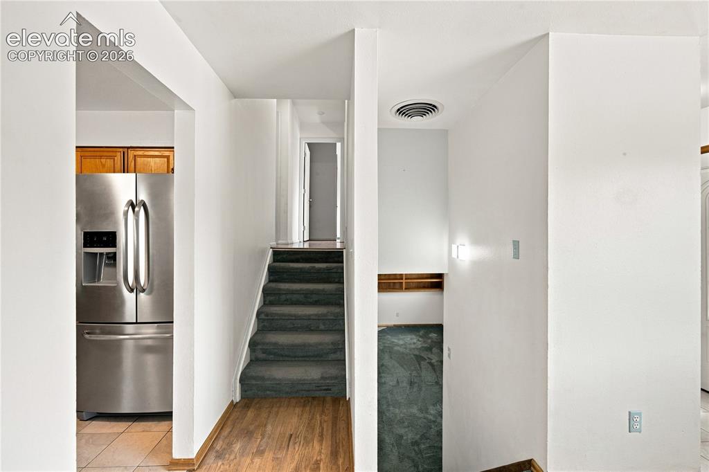 Image 13 of 39: Stainless steel refrigerator, wood-finish flooring, exposed shelving, and c