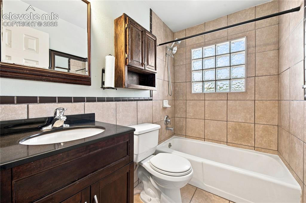 Image 14 of 39: Spa-inspired bathroom featuring a wood-finish vanity with dual sinks, tile 
