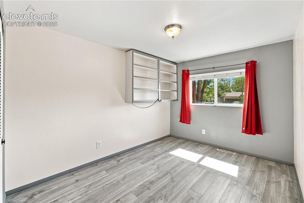 Image 17 of 39: Wood-finish flooring, built-in shelving, and a double-pane window