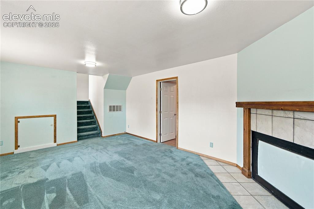 Image 19 of 39: Tile-surround fireplace with a wood mantle, recessed door with wood trim, a
