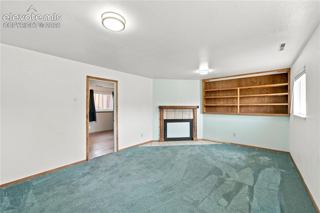 Image 20 of 39: Built-in wooden shelving, recessed fireplace with tile surround, and overhe