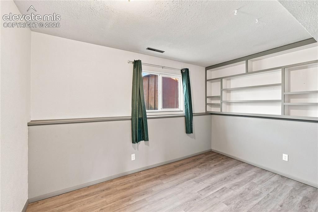 Image 22 of 39: Wood-finish flooring with built-in shelving, a single window, and a white a