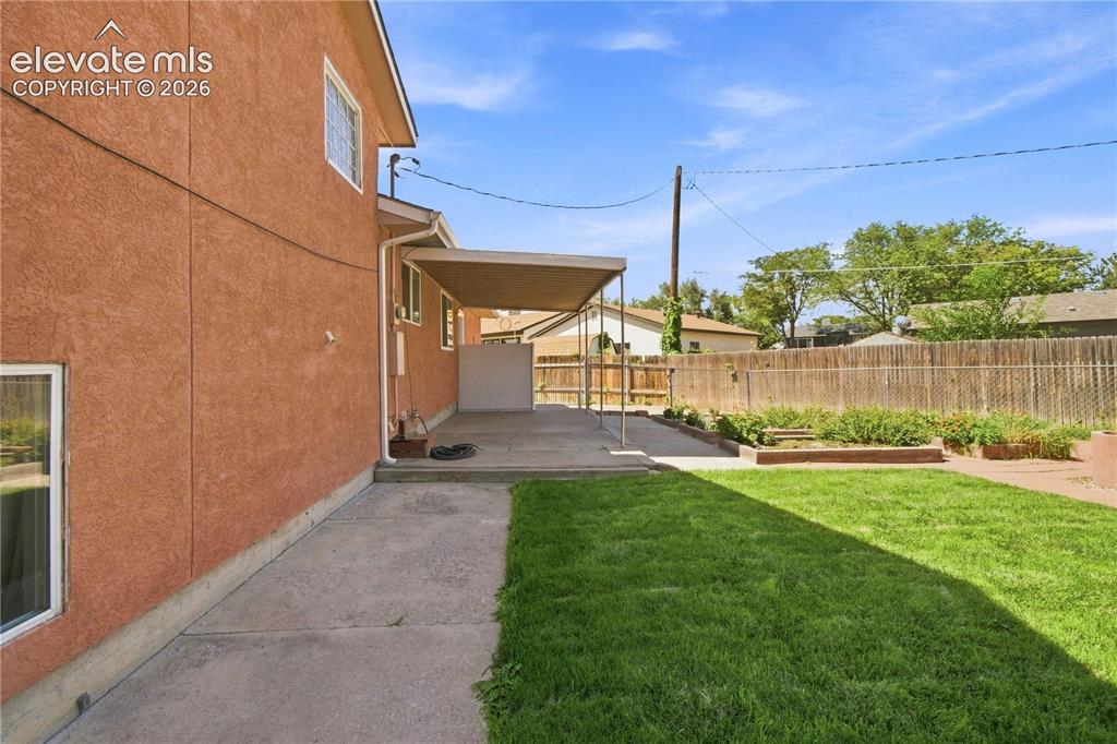Image 26 of 39: Stucco exterior, covered concrete patio, concrete pathway, fenced yard, and