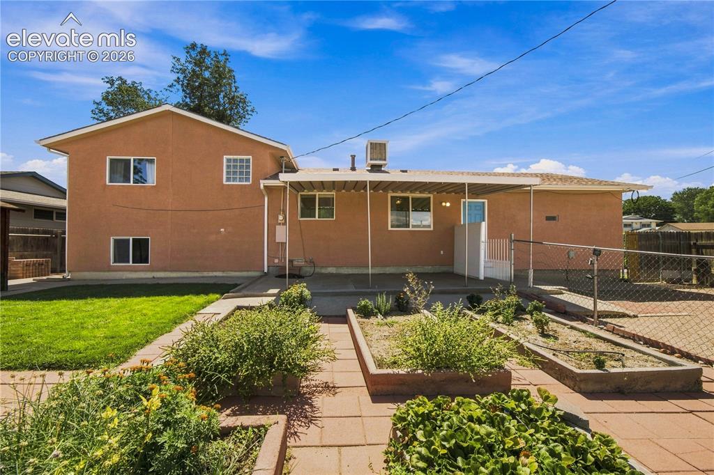 Image 30 of 39: Rear exterior with stucco finish, a covered patio, a fenced area, a grass l