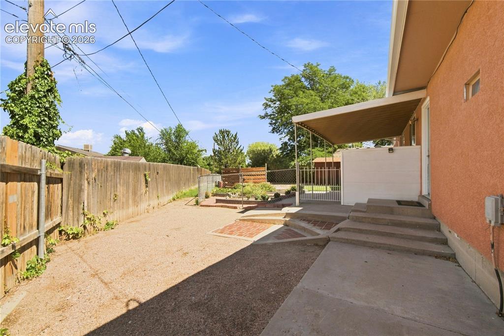 Image 32 of 39: Expansive rear yard featuring a wood privacy fence, gravel surface, and con