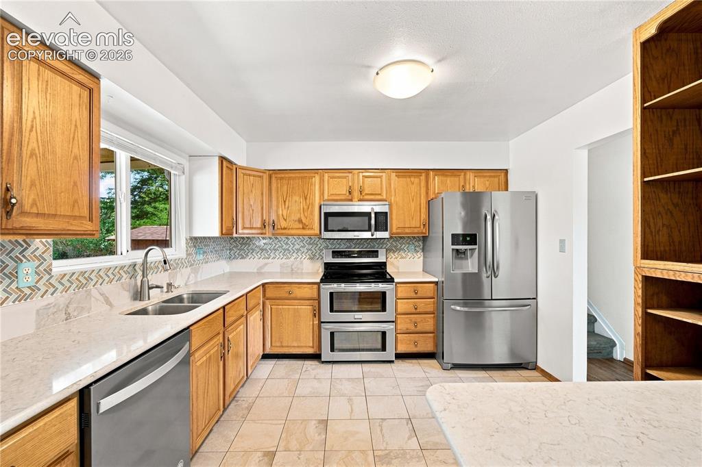 Image 9 of 39: Kitchen featuring wood cabinetry, stainless steel appliances, a double basi