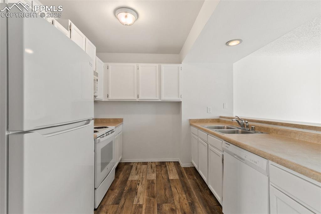 Image 10 of 33: Kitchen featuring white appliances, dark wood-type flooring, a sink, white