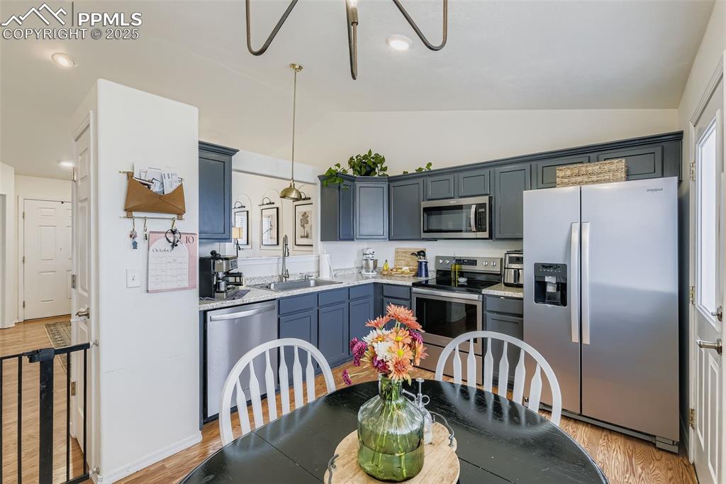 Image 12 of 28: Kitchen with stainless steel appliances, lofted ceiling, light wood-style f