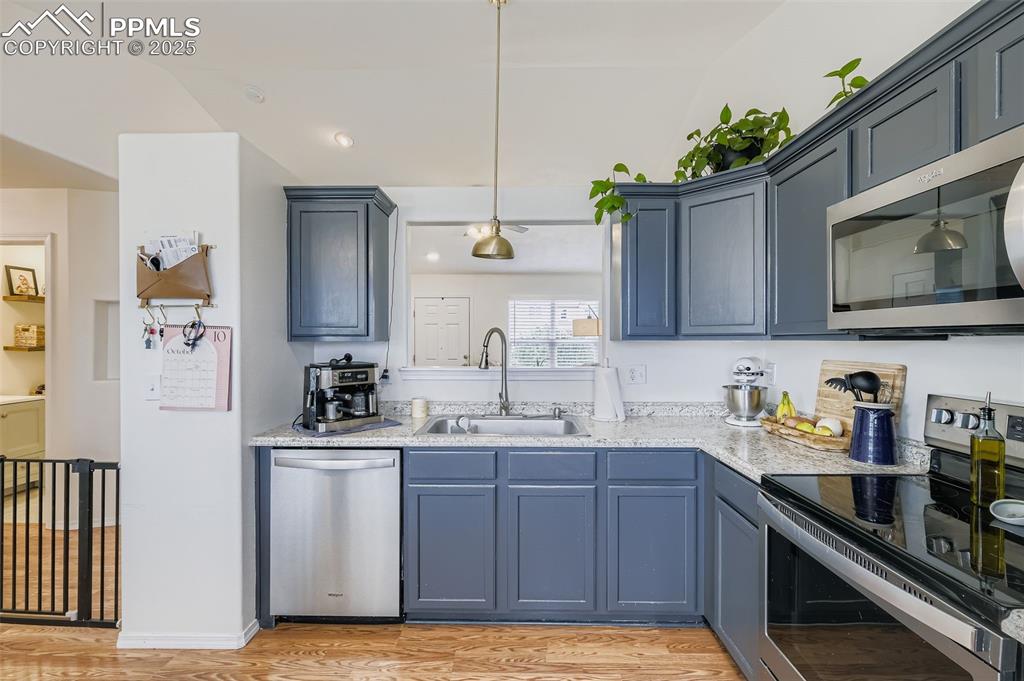 Image 13 of 28: Kitchen with appliances with stainless steel finishes, pendant lighting, li