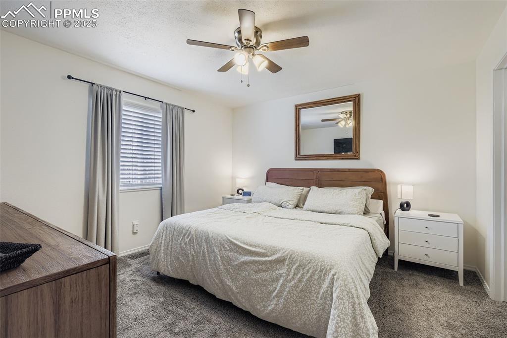 Image 15 of 28: Bedroom with ceiling fan, carpet floors, and a textured ceiling
