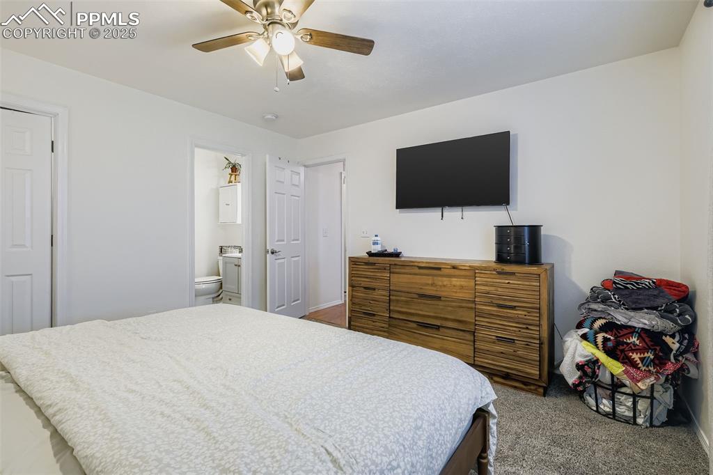 Image 17 of 28: Carpeted bedroom with ceiling fan and ensuite bath