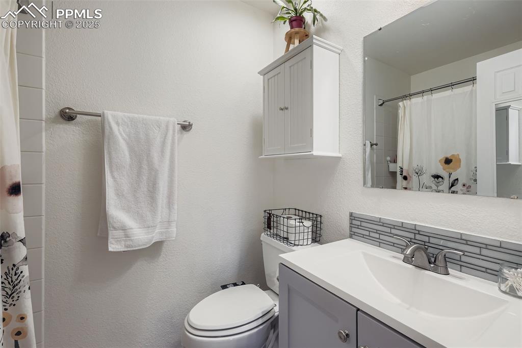 Image 19 of 28: Full bath with a textured wall, a shower with shower curtain, vanity, and d