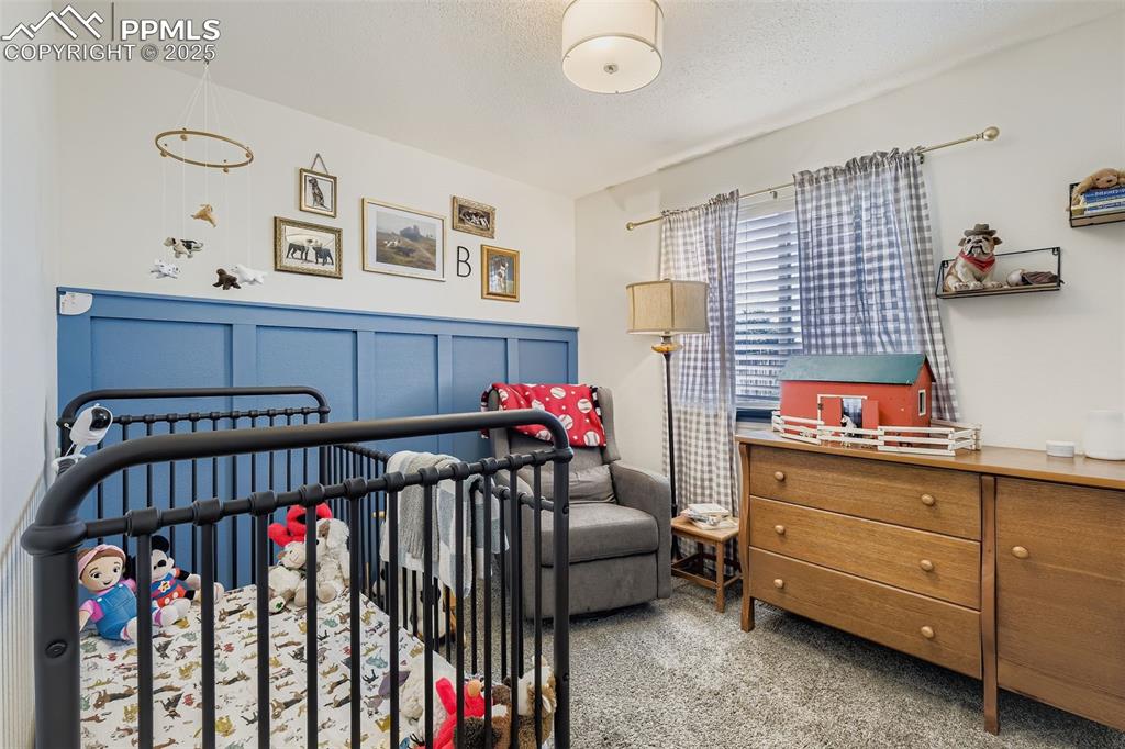 Image 21 of 28: Carpeted bedroom featuring a nursery area and a textured ceiling