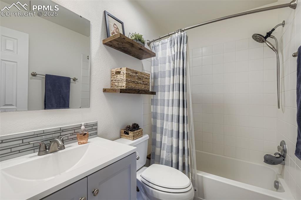 Image 22 of 28: Bathroom featuring a textured wall, shower / bath combo with shower curtain
