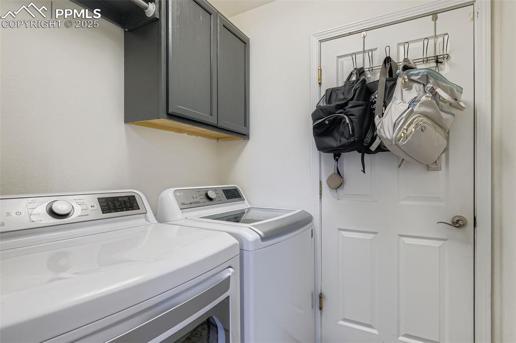 Image 24 of 28: Washroom with cabinet space and washer and clothes dryer