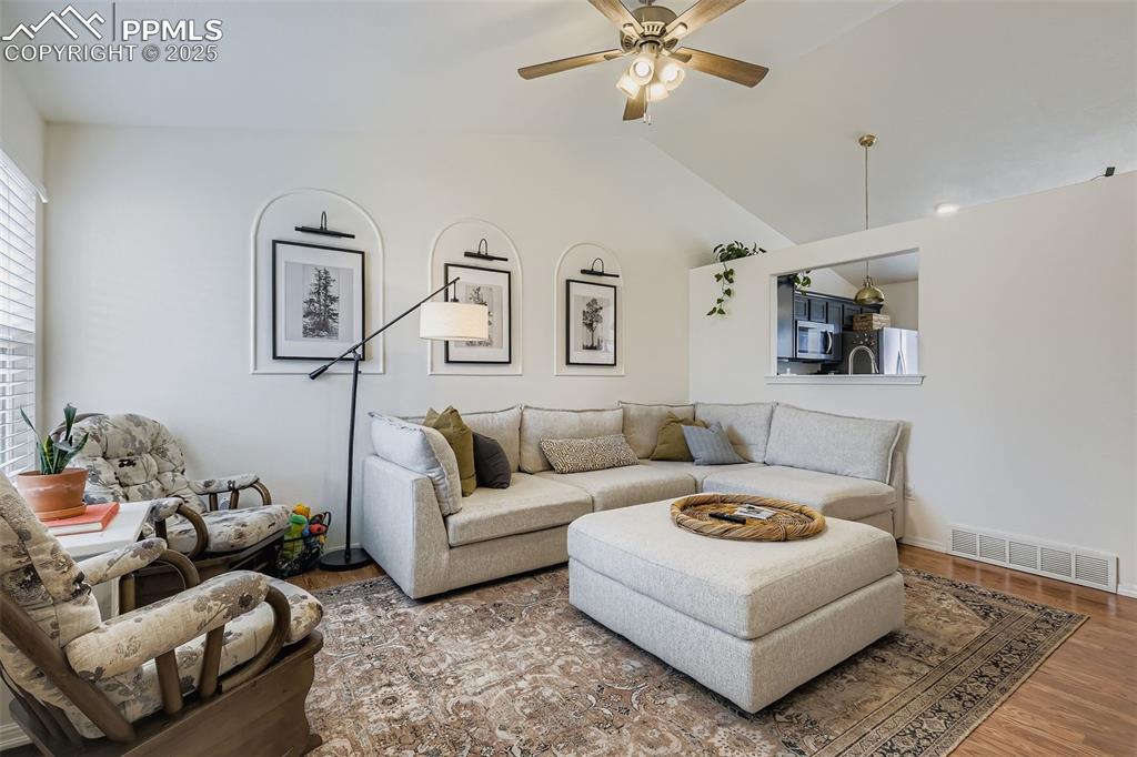 Image 5 of 28: Living area with wood finished floors, a ceiling fan, and lofted ceiling