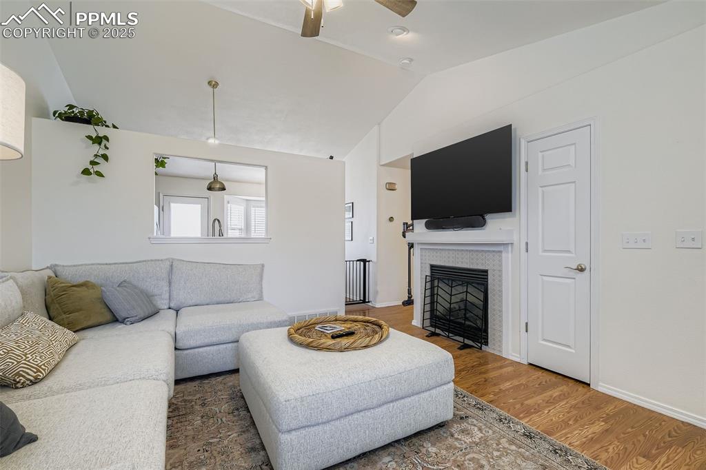 Image 6 of 28: Living room with wood finished floors, a fireplace, vaulted ceiling, and ce