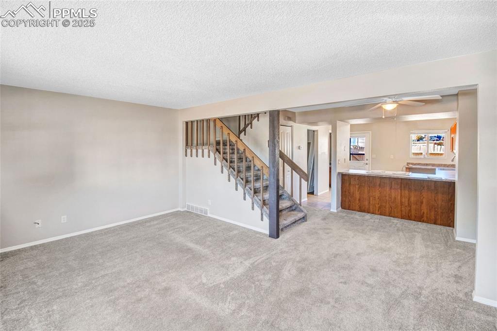 Image 11 of 35: Unfurnished living room with light colored carpet, a ceiling fan, a texture