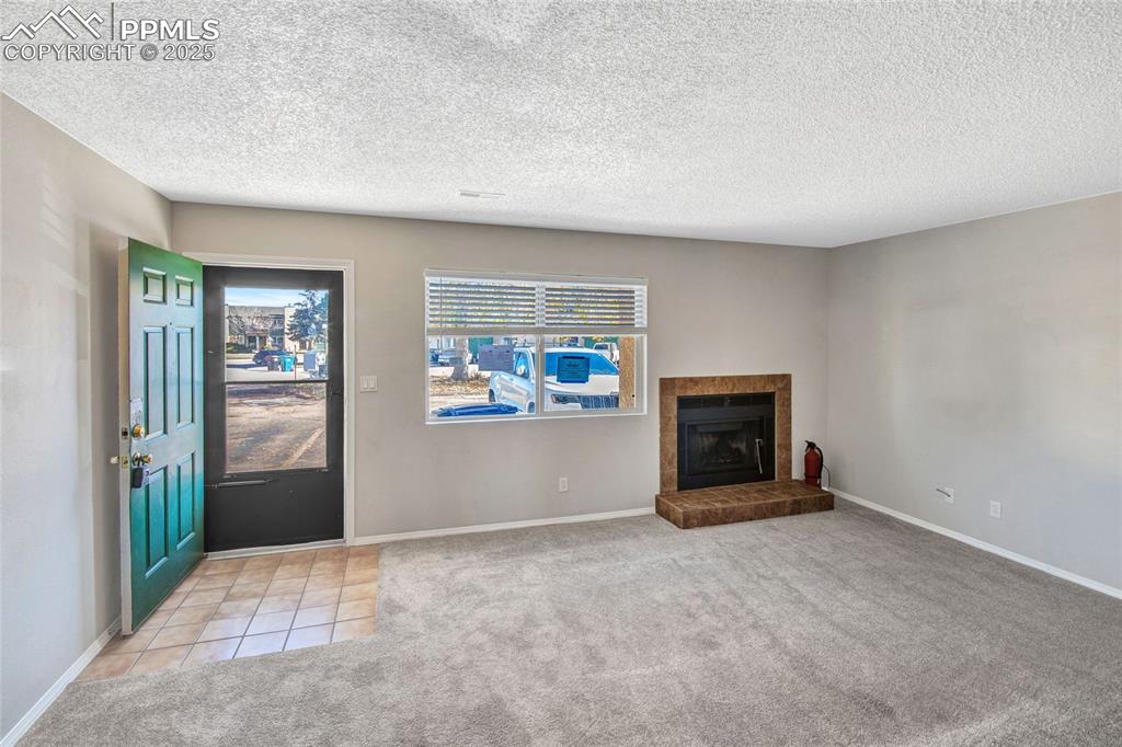 Image 12 of 35: Unfurnished living room featuring light carpet, a textured ceiling, light t