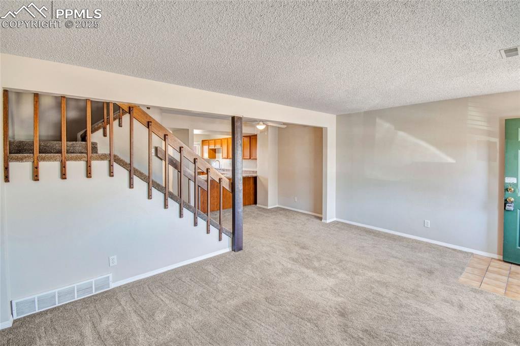 Image 16 of 35: Basement featuring carpet floors, stairway, and a textured ceiling