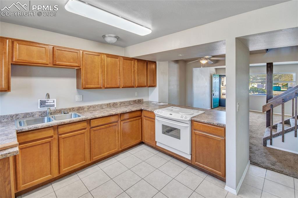 Image 20 of 35: Kitchen with white range with electric stovetop, light tile patterned floor