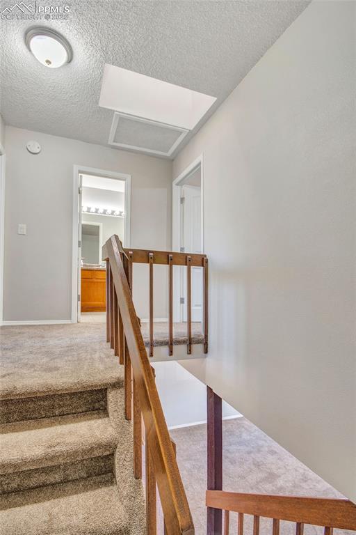 Image 21 of 35: Stairway with carpet floors and a textured ceiling