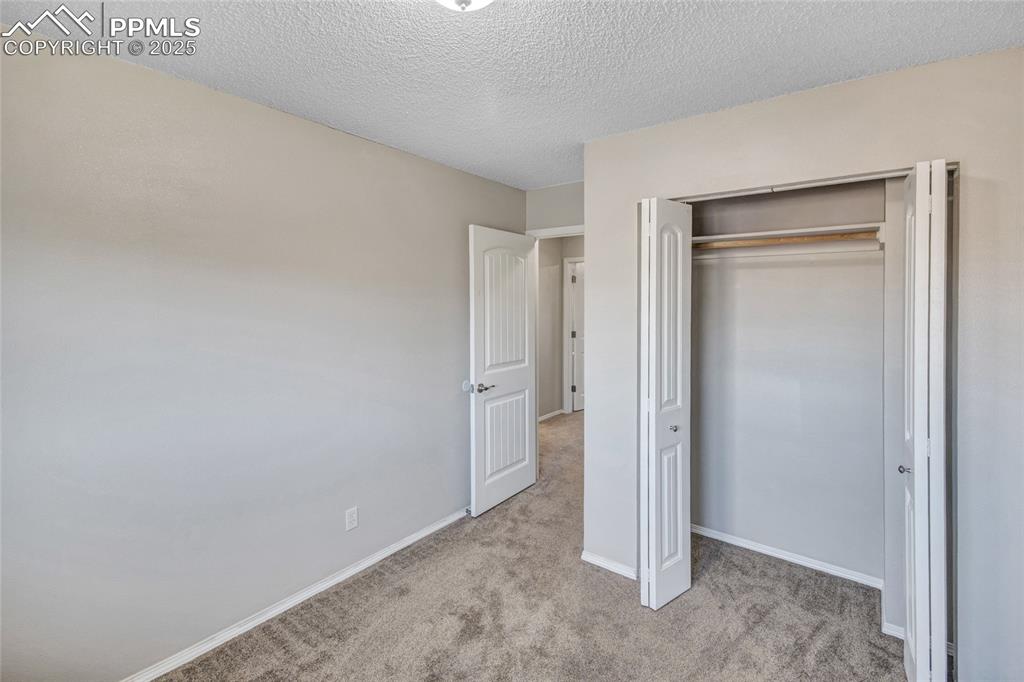 Image 23 of 35: Unfurnished bedroom with light colored carpet, a textured ceiling, and a cl