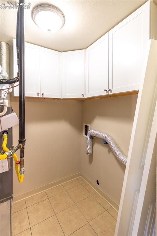 Image 30 of 35: Laundry room featuring cabinet space, light tile patterned floors, and hook