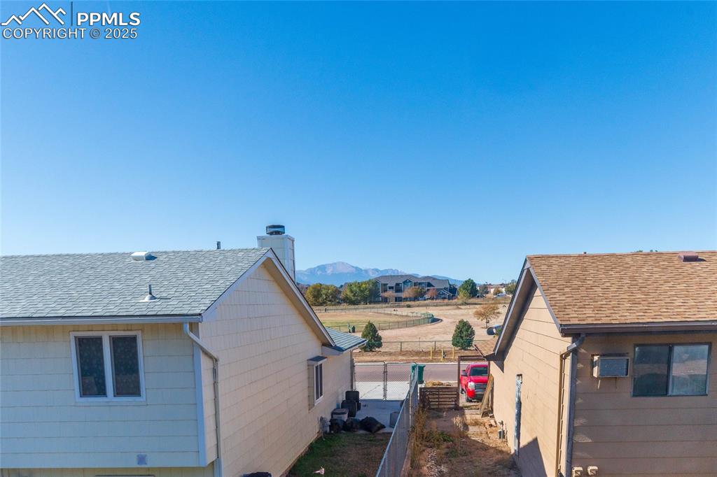 Image 9 of 35: View of side of home featuring a shingled roof, a chimney, and a mountain v