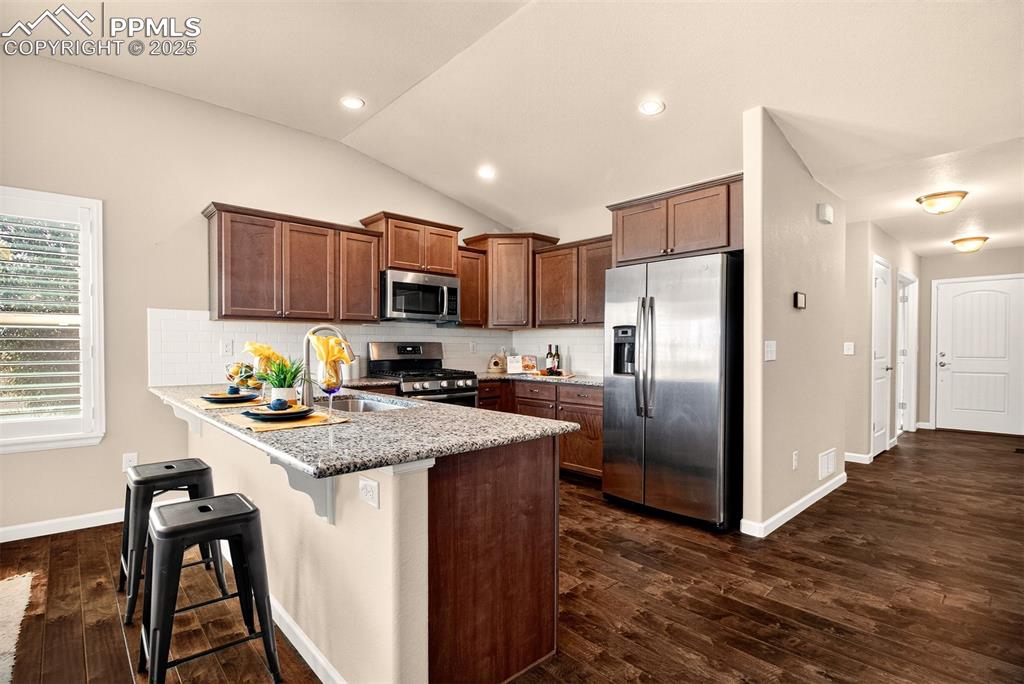 Image 11 of 37: Open layout kitchen, dining and living space with vaulted ceilings