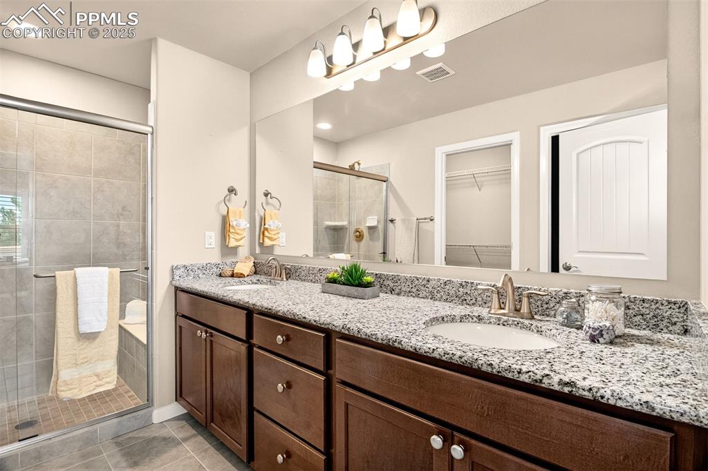 Image 22 of 37: Master bathroom features dual vanities with granite countertops and a walk-
