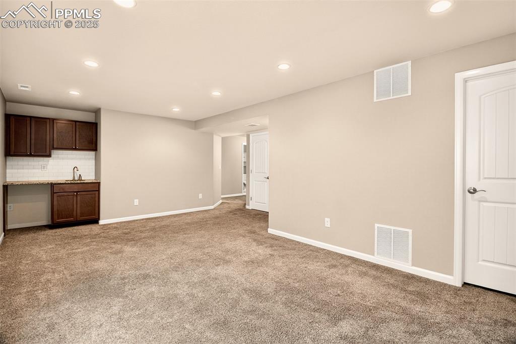 Image 24 of 37: Head downstairs to a spacious family / rec room with wet bar
