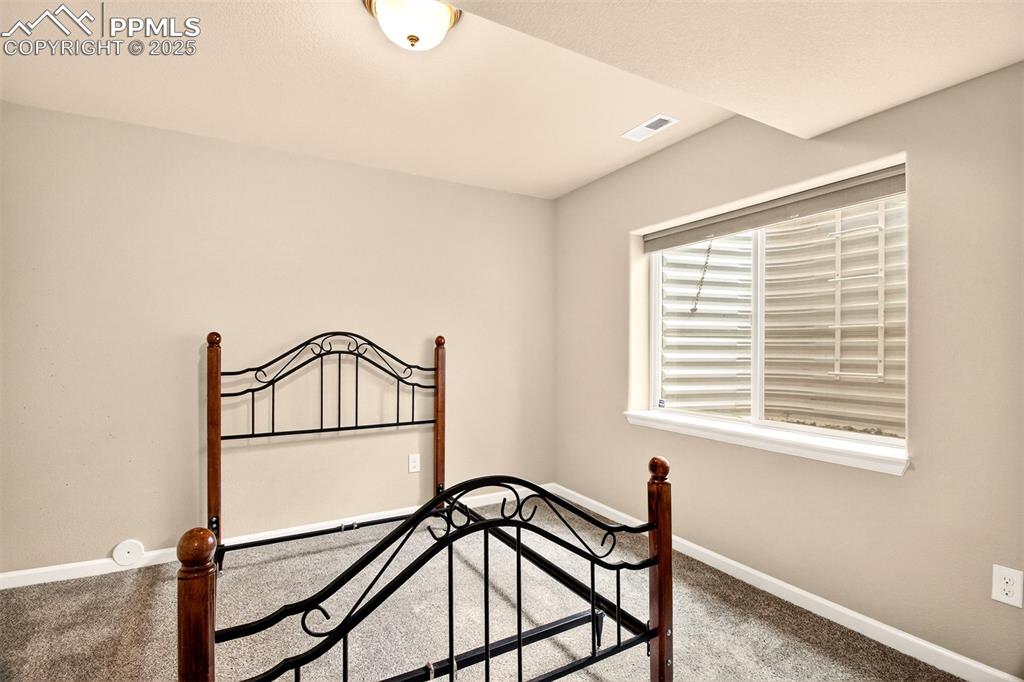 Image 26 of 37: Basement level bedroom with a large window to let in light