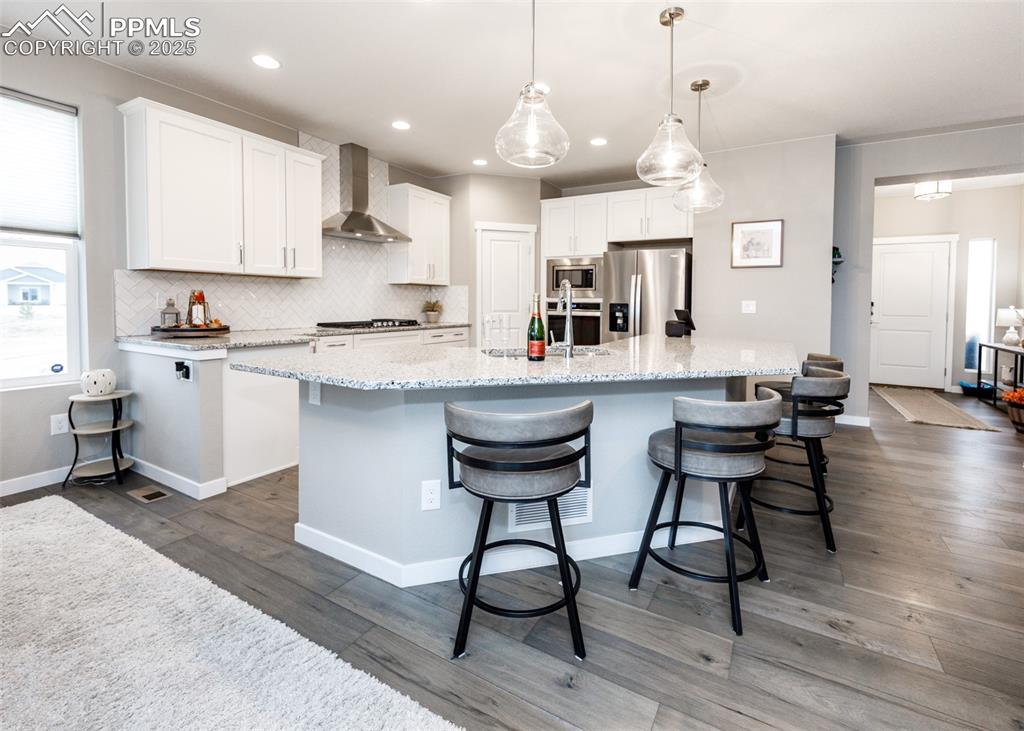 Image 11 of 37: Stylish kitchen with white cabinetry, island, and decorative backsplash.
