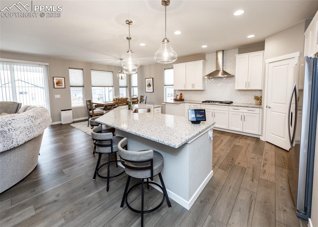 Image 14 of 37: he kitchen features light wood-style flooring, white cabinetry, a decorativ
