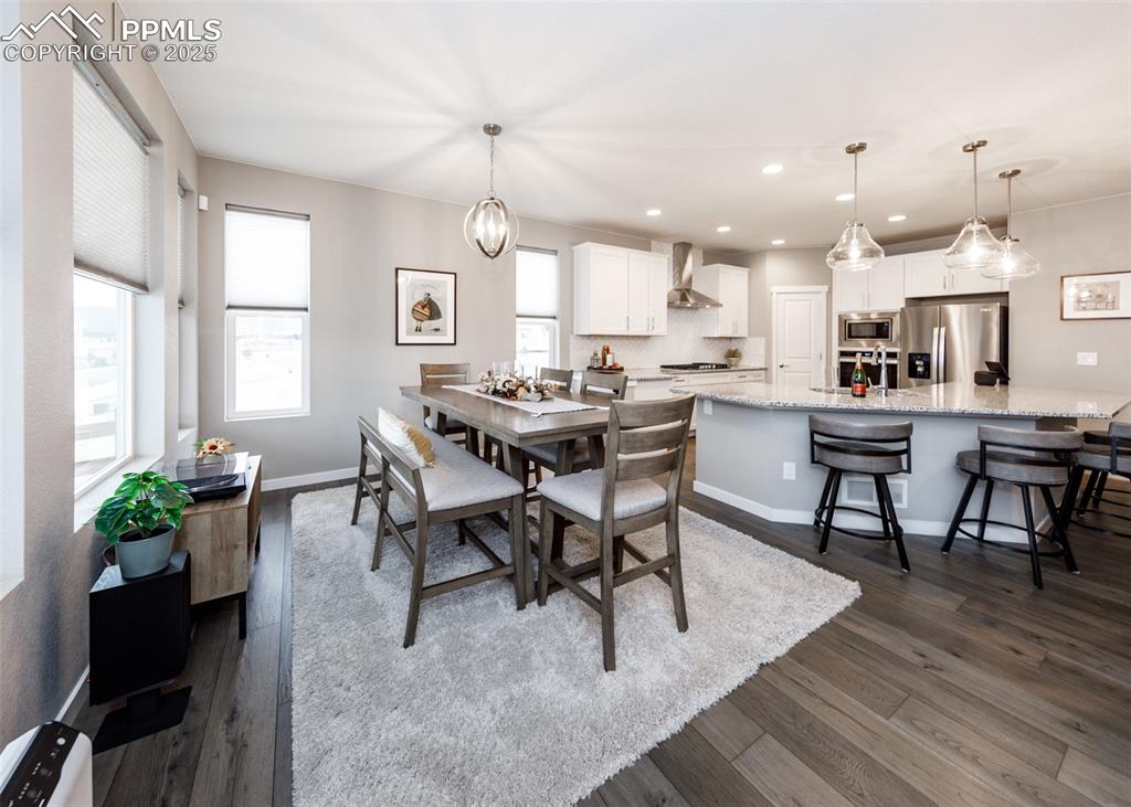 Image 16 of 37: Dining room features light wood floors, a ceiling fan, chandelier, and scen