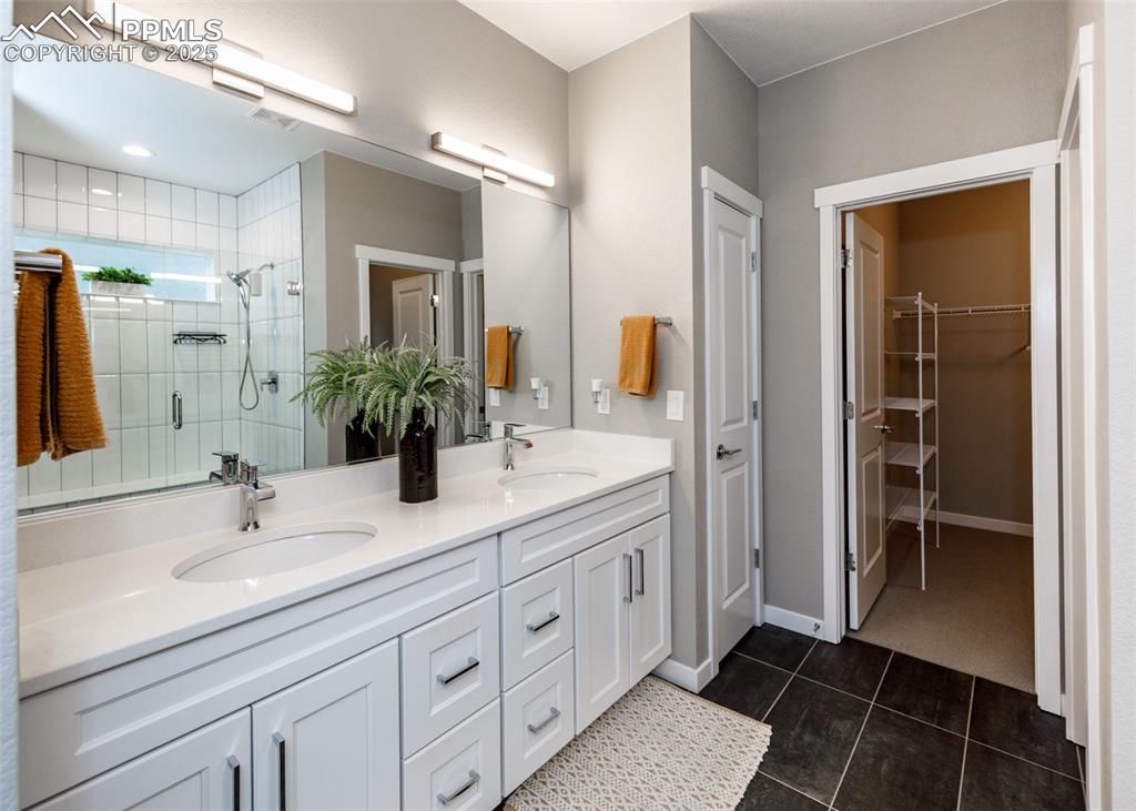 Image 20 of 37: Bathroom features a double vanity, stall shower, and stylish tile-patterned