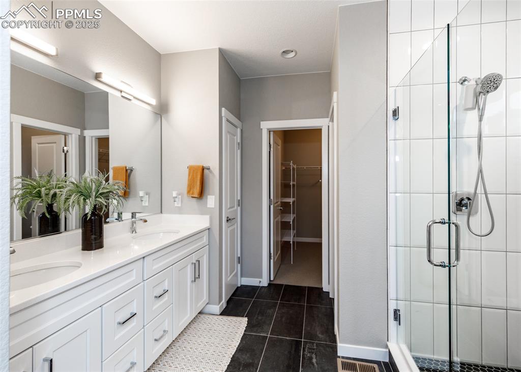 Image 21 of 37: Bright bathroom with a double vanity, stall shower, and elegant tile-patter