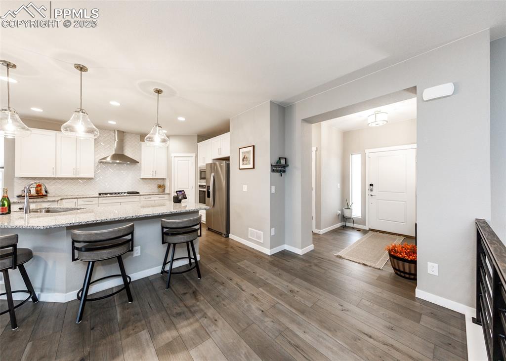 Image 8 of 37: Entry into the beautiful home and kitchen with breakfast bar and elegant wh