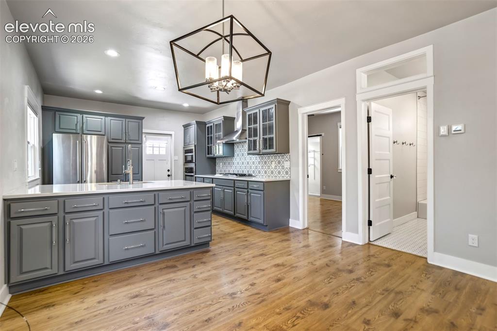 Image 12 of 50: Kitchen featuring a large island with white countertops, grey cabinetry, st