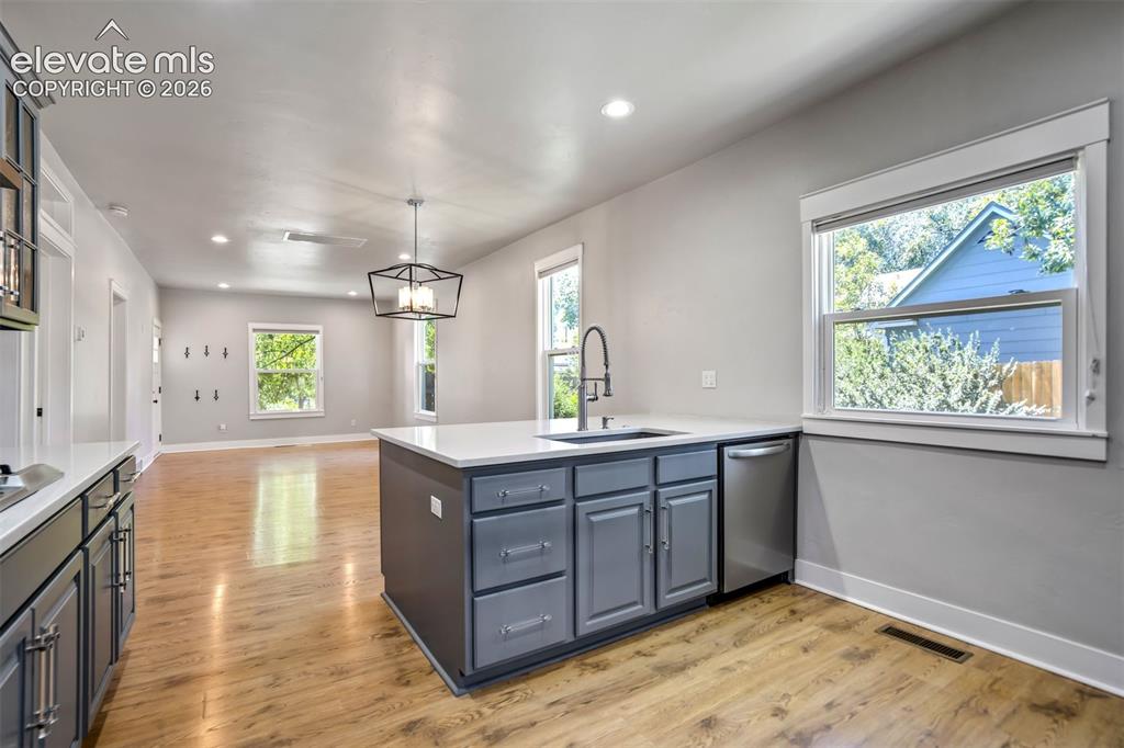 Image 13 of 50: Open-concept kitchen featuring an island with a built-in sink and dishwashe