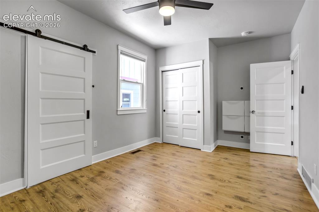 Image 19 of 50: Spacious room featuring wood-finish flooring, a modern ceiling fan, and a b