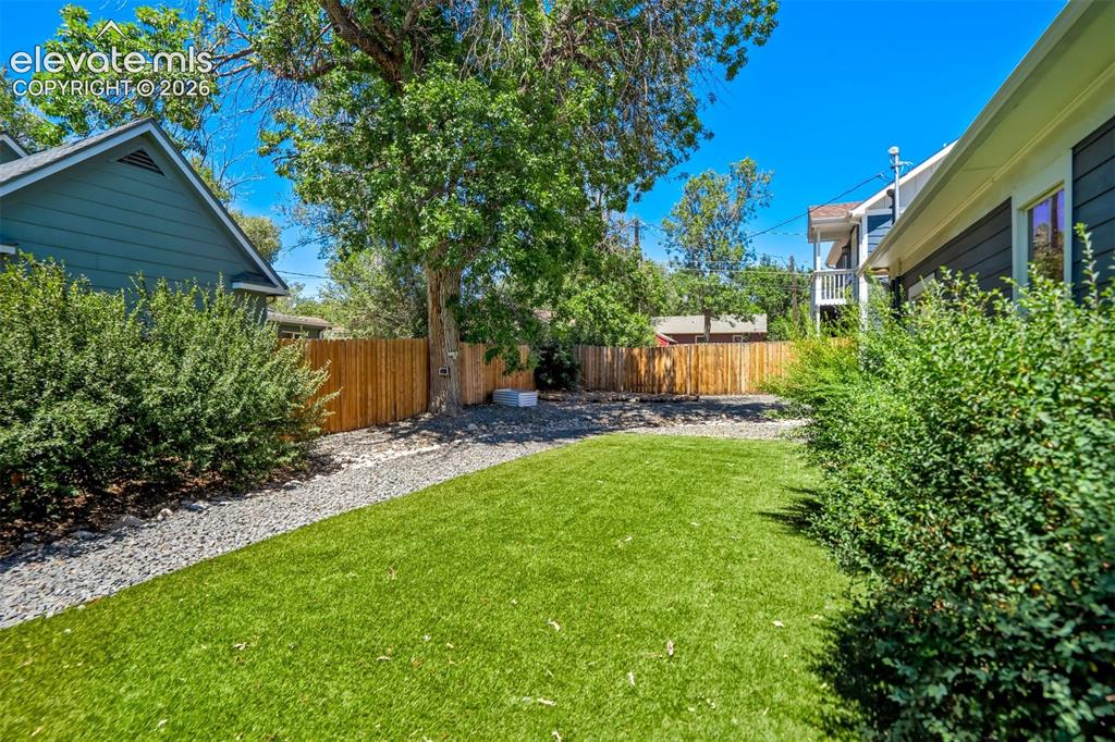 Image 25 of 50: Expansive backyard featuring artificial turf, a wood privacy fence, and mat