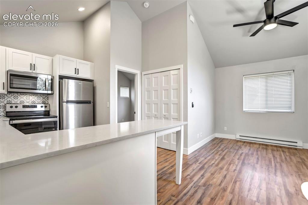 Image 31 of 50: Kitchen in garage apartment featuring a vaulted ceiling and wood-finish flo