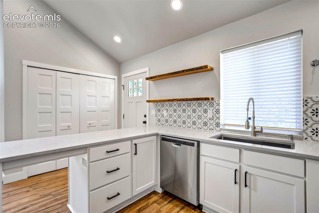 Image 33 of 50: Kitchen area featuring white cabinetry with black hardware, stainless steel